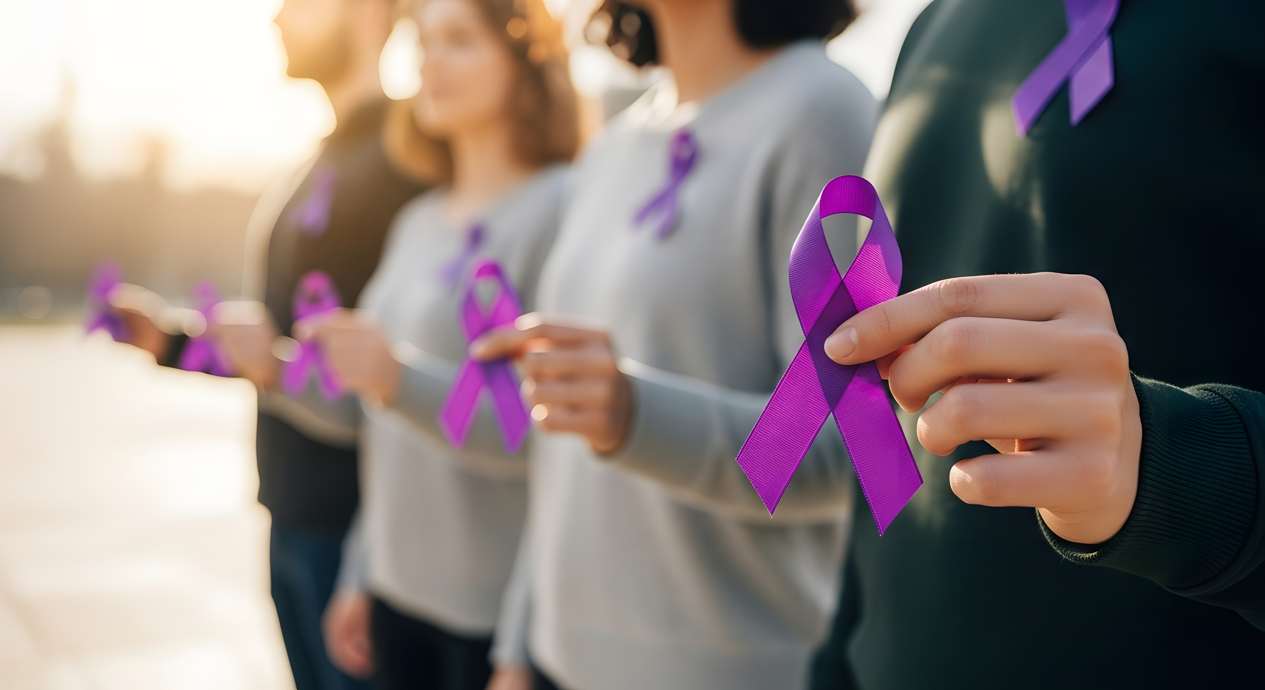 Foto com quatro pessoas, cada uma delas a segurar na ponta dos dedos um laço roxo